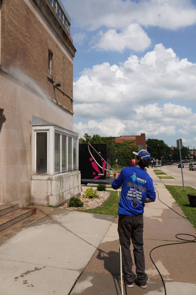 Crew member washing the exterior of a brick building